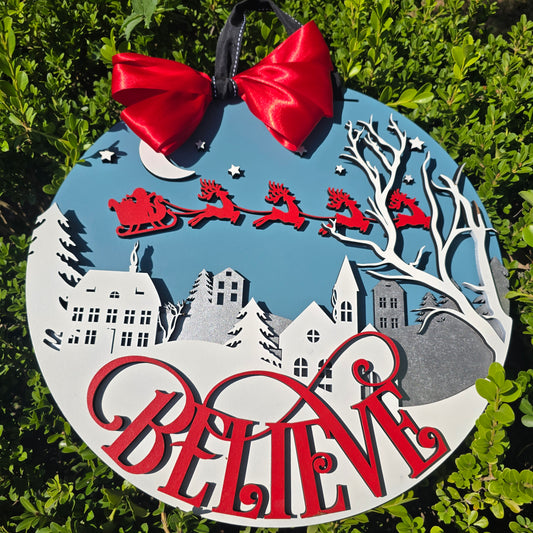 “Believe” Christmas Wall Sign – Santa’s Sleigh Over Winter Town